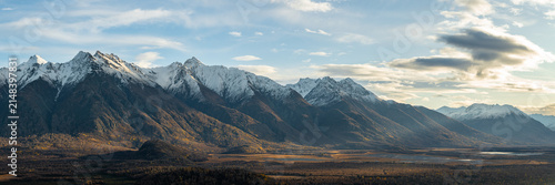 View of Chugach mountains in Alaska in fall, snow-capped peaks in background and valley below in sunrise lighting