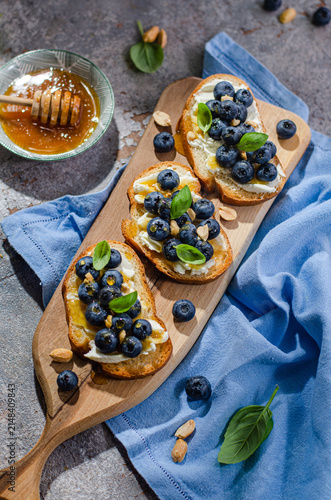 Blueberry, peanut, and cream cheese toasts on a wooden board