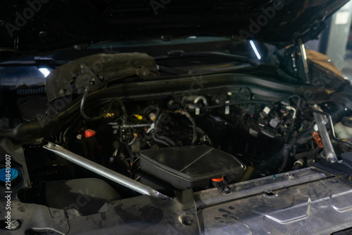 View of inner car parts under open hood in repair shop closeup. Vehicle prepared for maintenance of engine at modern service station