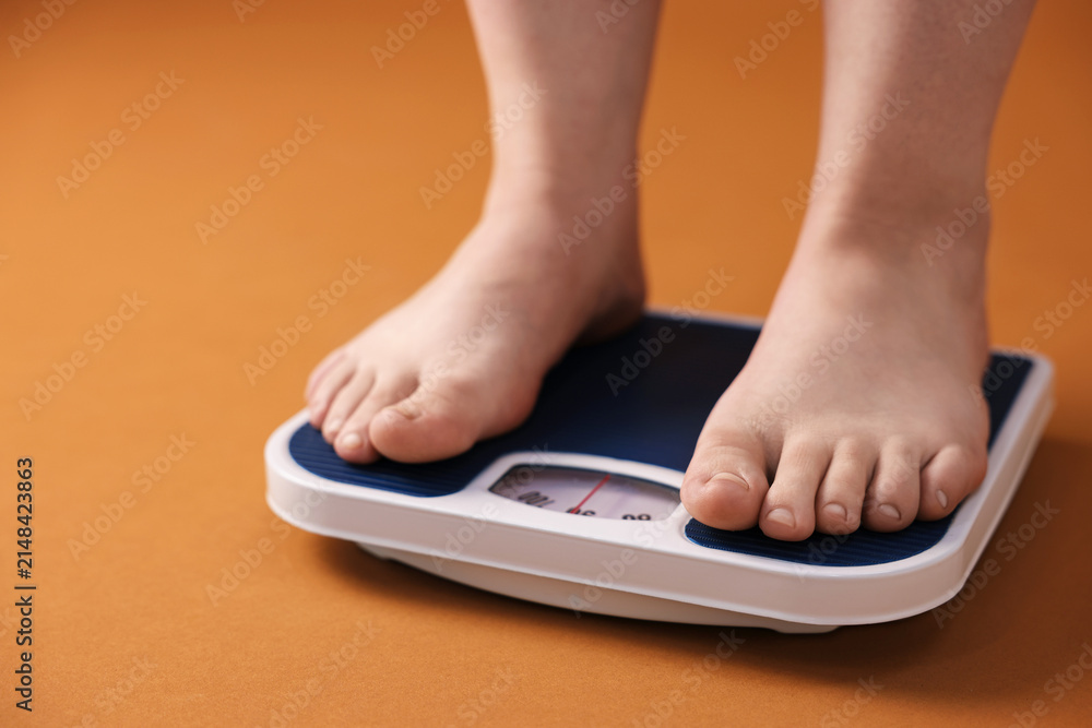 Fototapeta premium Overweight woman on scale against brown background, closeup. Space for text