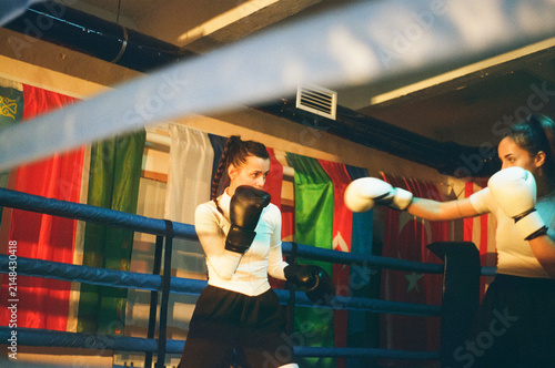 Woman boxer strikes sparring female partner in ring. Real boxing fight