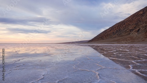 Expansive Salt Flat Landscape with Dramatic Sky and Mountainous Terrain at Sunset
