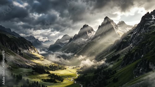 Majestic Alpine Peaks Shrouded in Mist with Golden Valley Sunbeams and Dramatic Clouds