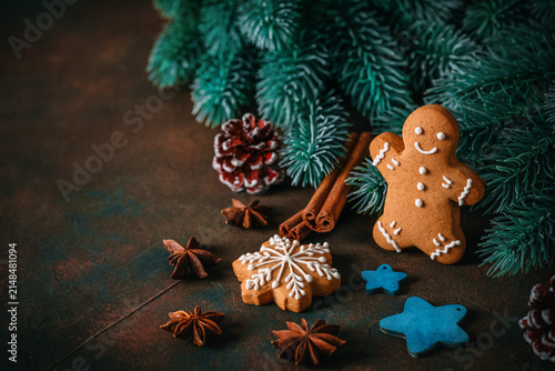 Gingerbread man on dark grunge background with Christmas decorations, fir branches, spices, stars, selective focus, copy space.