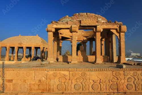 View of the historic Chaukhandi tombs featuring intricate sandstone carvings and ancient funerary architecture under a clear blue sky in Karachi, Sindh, Pakistan.