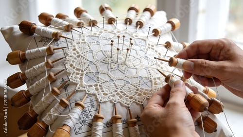 Artisan hands making traditional Vamberk bobbin lace with wooden bobbins, Czech intangible cultural heritage, EU protected designation