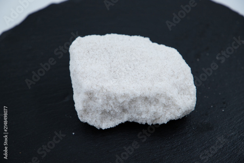 Quadro su tela Macro eye-level shot of white rock salt chunks and mineral crystals on a black slate