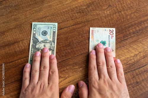 Fotografie Hands comparing US dollar and Colombian peso banknotes