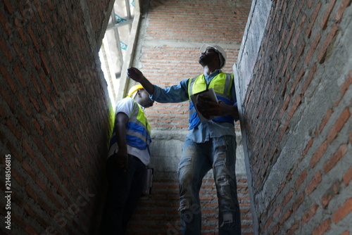 Obraz na płótnie African foreman and young worker in safety vests test the strength of the masonr