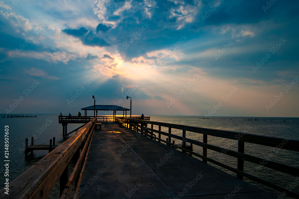 Fototapeta premium Sunset at pier with Silhouette people relaxing and enjoying the view over water