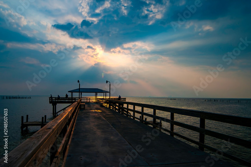 Quadro su tela Sunset at pier with Silhouette people relaxing and enjoying the view over water