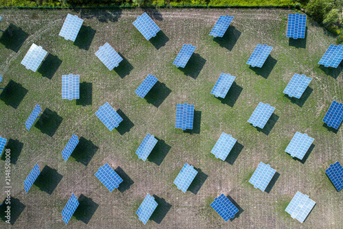 Aerial view of a solar farm with rows of photovoltaic panels installed in a green field in Quattordio, Piedmont, Italy.