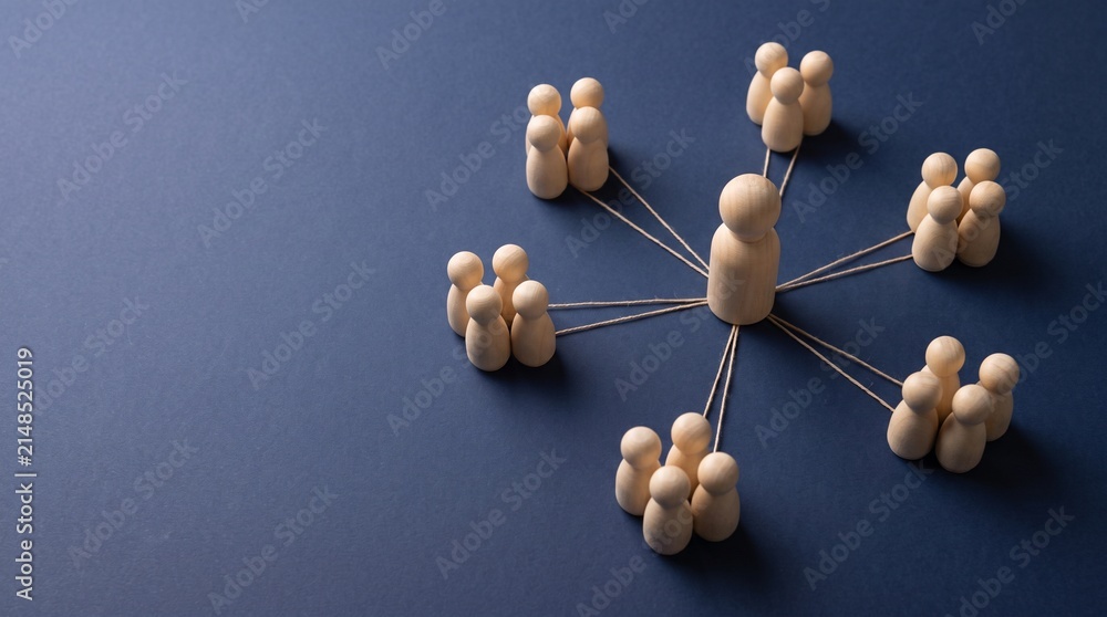 Obraz premium Central wooden human figure linked to various groups of smaller figures via strings on minimalist dark blue background.