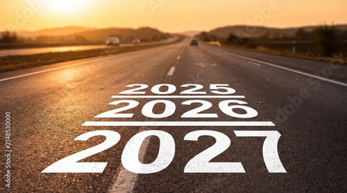 Years 2025, 2026 and 2027 painted on an asphalt highway at sunset