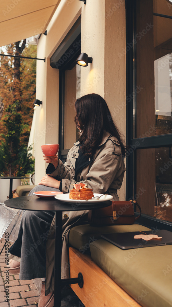 Fototapeta premium Woman enjoying coffee and pastry at an outdoor cafe during autumn