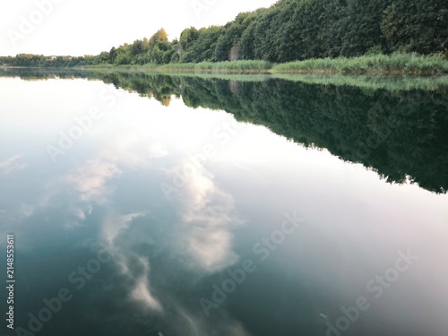 Fotografie Reflection of the sky and forest in the mirror-like water of the river