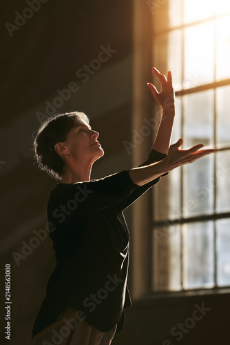Serene Woman Reaching Toward Golden Sunlight with Arms Extended, Creating a Peaceful Contemplative Silhouette with Warm Light and Copy Space. Vertical 2:3
