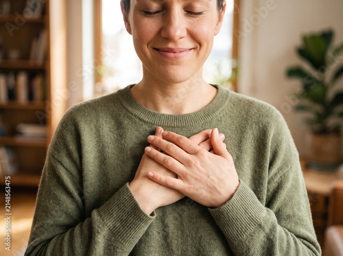 Happy woman holding hands on her chest feeling grateful and peaceful at home