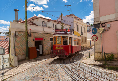 Historic red Lisbon tram on narrow cobblestone street in Alfama Portugal