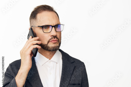 Obraz na plátne A professional businessman on a colored isolated background, speaking on a mobile phone with a focused, confident expression, conveying clear communication and decisive business mindset