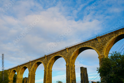 The historic Moorswater Viaduct near Liskeard, Cornwall, spans a deep valley with eight striking semi-circular arches built from snecked rock-faced slatestone and granite. 