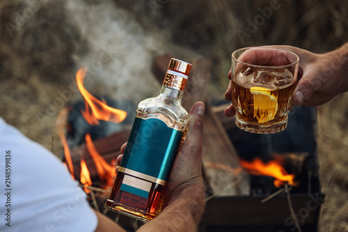 Hands holding whiskey bottle and glass