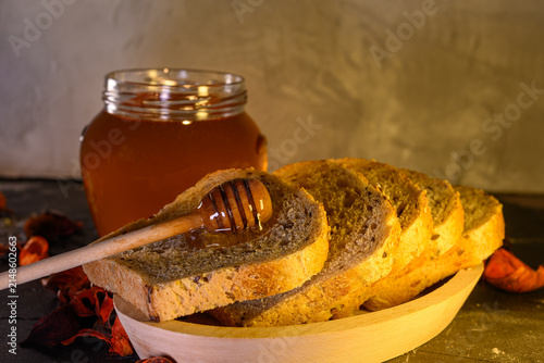 Konstfotografi Golden honey and fresh bread slices beside glass jar in warm rustic kitchen sett