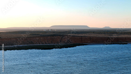 Aerial view of Matthew Flinders Red Cliff Lookout overlooking the Spencer Gulf with rugged red cliffs and distant hills under a soft sunset sky Port Augusta West, South Australia, Australia.
