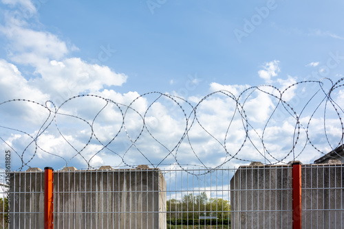 Konstfotografi Concertina razor wire loops above a metal security fence
