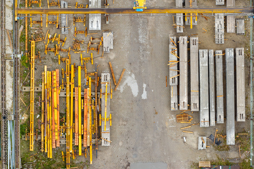 Aerial view of prestressed concrete elements and yellow metal construction frames arranged in a storage yard in Poland.