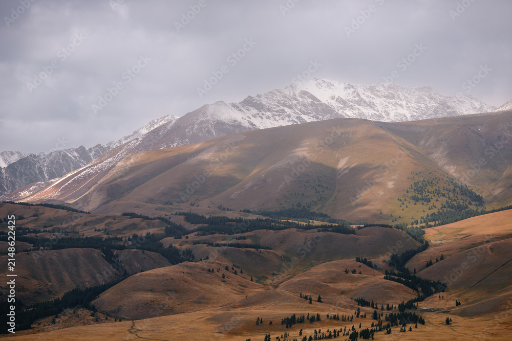 Obraz premium Majestic mountain landscape with snow-capped peaks and rolling hills