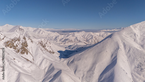 Aerial view of the snow-covered peaks and rugged terrain of Lindis Pass in the Otago Region, New Zealand.