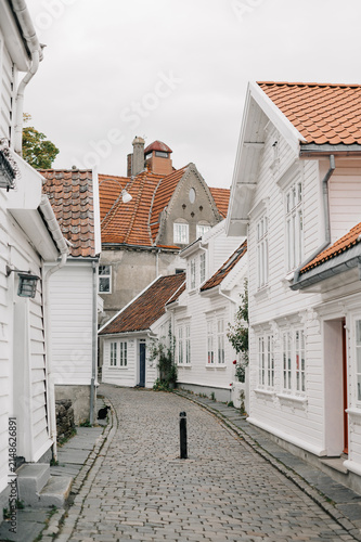 Charming white wooden houses line a cobblestone street in Norway