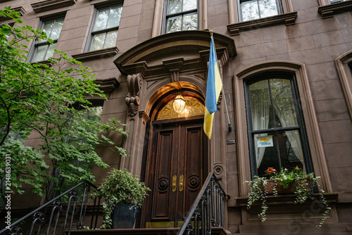 Фотография An ornate brownstone doorway with carved stone details stands beneath a glowing lantern in Manhattan