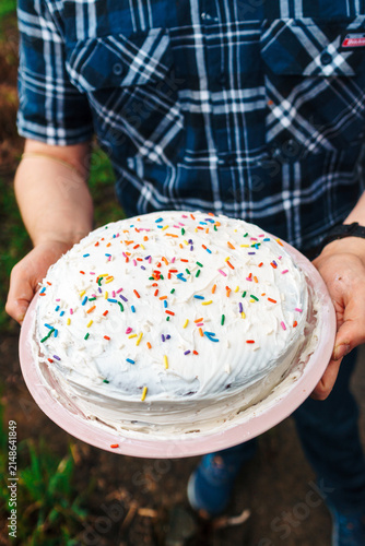 Young man holding birthday cake with sprinkles