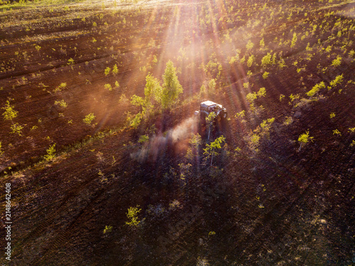 Aerial view of an off-road vehicle driving through a field at golden hour with dust kicking up in Sortavala, Respublika Kareliya, Russia.