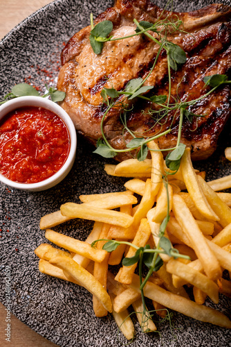 Grilled bone-in steak with French fries and red sauce