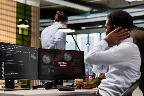 Canvas Print Technicians collaborate in a technology startup office to resolve a critical error alert on screen, troubleshooting system warnings and equipment failure together during team problem solving