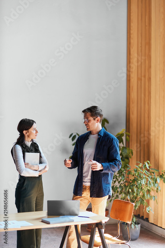 Business professionals discussing work in a modern office, collaborating on a project and sharing ideas during a meeting with a laptop and documents on the table