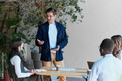 Young male leader presenting business strategy during a collaborative team meeting, discussing new ideas and growth plans with diverse colleagues in a modern office