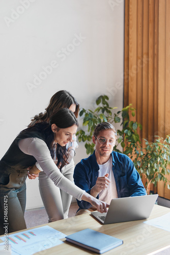 Business professionals collaborating and brainstorming new ideas on a laptop in a modern office, working together on a project, analyzing data, and finding creative solutions