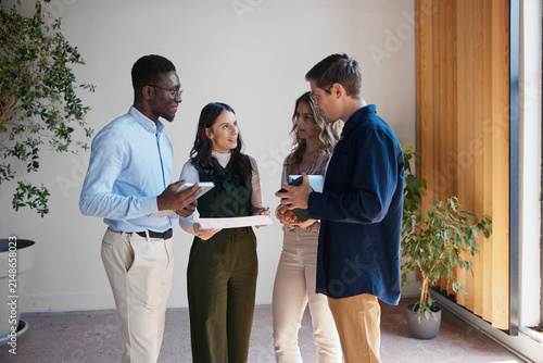 Diverse business team collaborating during an informal meeting, discussing new ideas and strategy in a modern office, showing teamwork and communication