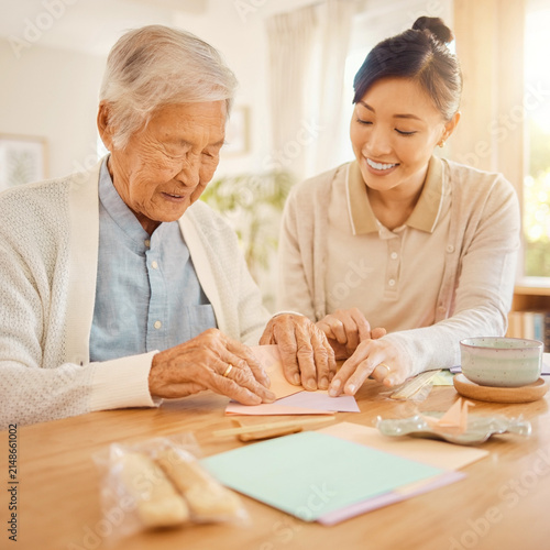 Elderly Japanese person doing origami with a caregiver at table