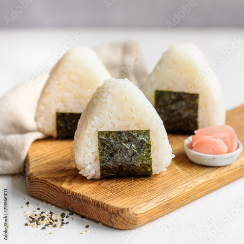 Fresh Japanese rice balls onigiri wrapped in nori on wooden board