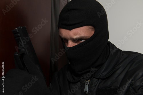 Foto Burglar Standing Behind The Door With A Gun