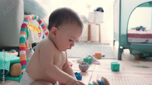 Curious baby boy playing with educational wooden toys at home