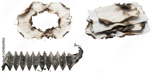 A collection of charred paper pieces with burned edges, holes, ash, and curled corners.