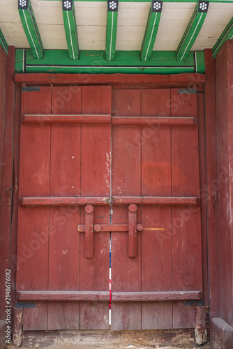Fotografie Red wooden double door with painted eaves on a traditional building in south korea