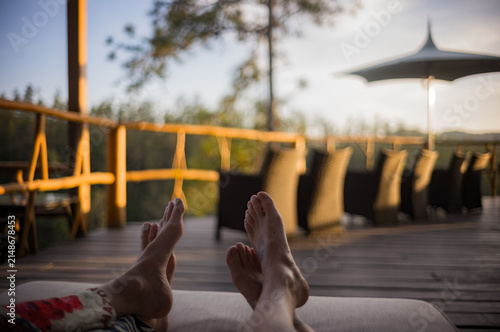 Two people's feet relaxing on a chair at sunset in Eastern Belize, Central America