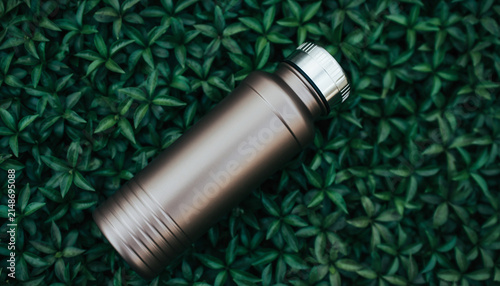 Shiny stainless steel bottle on textured green background.